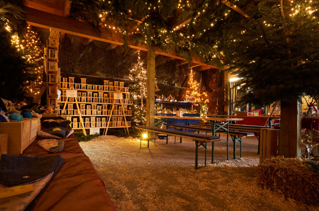Winterlicht geschmückte Hütte mit Verkaufsständen, Tischen und Bänken